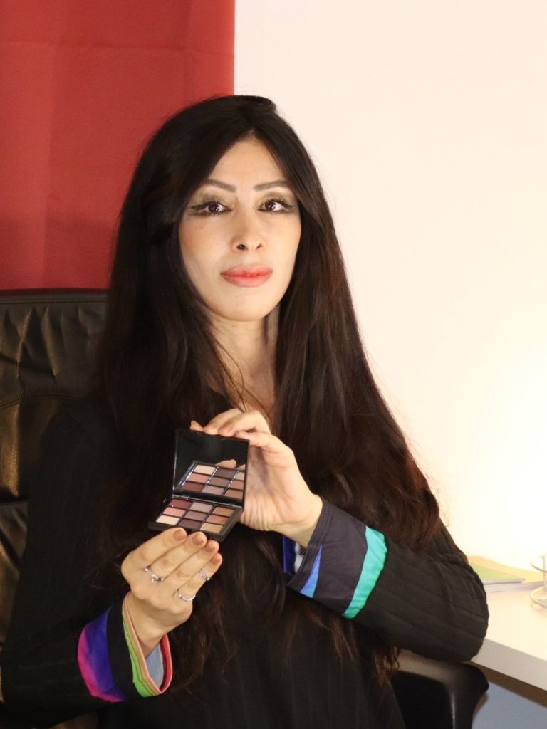 Femme avec de longs cheveux noirs tenant un boîtier de maquillage.